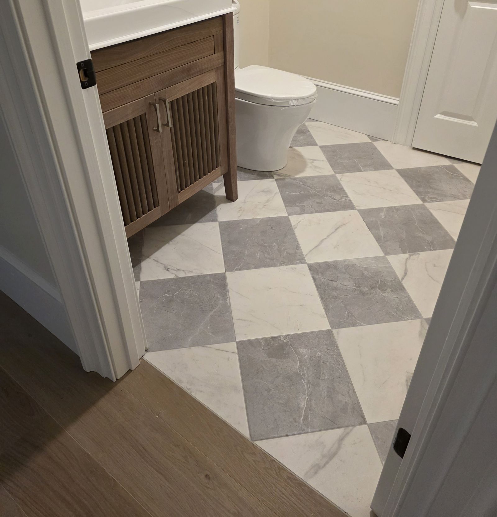 Powder room with checkerboard marble tile and fluted wood vanity