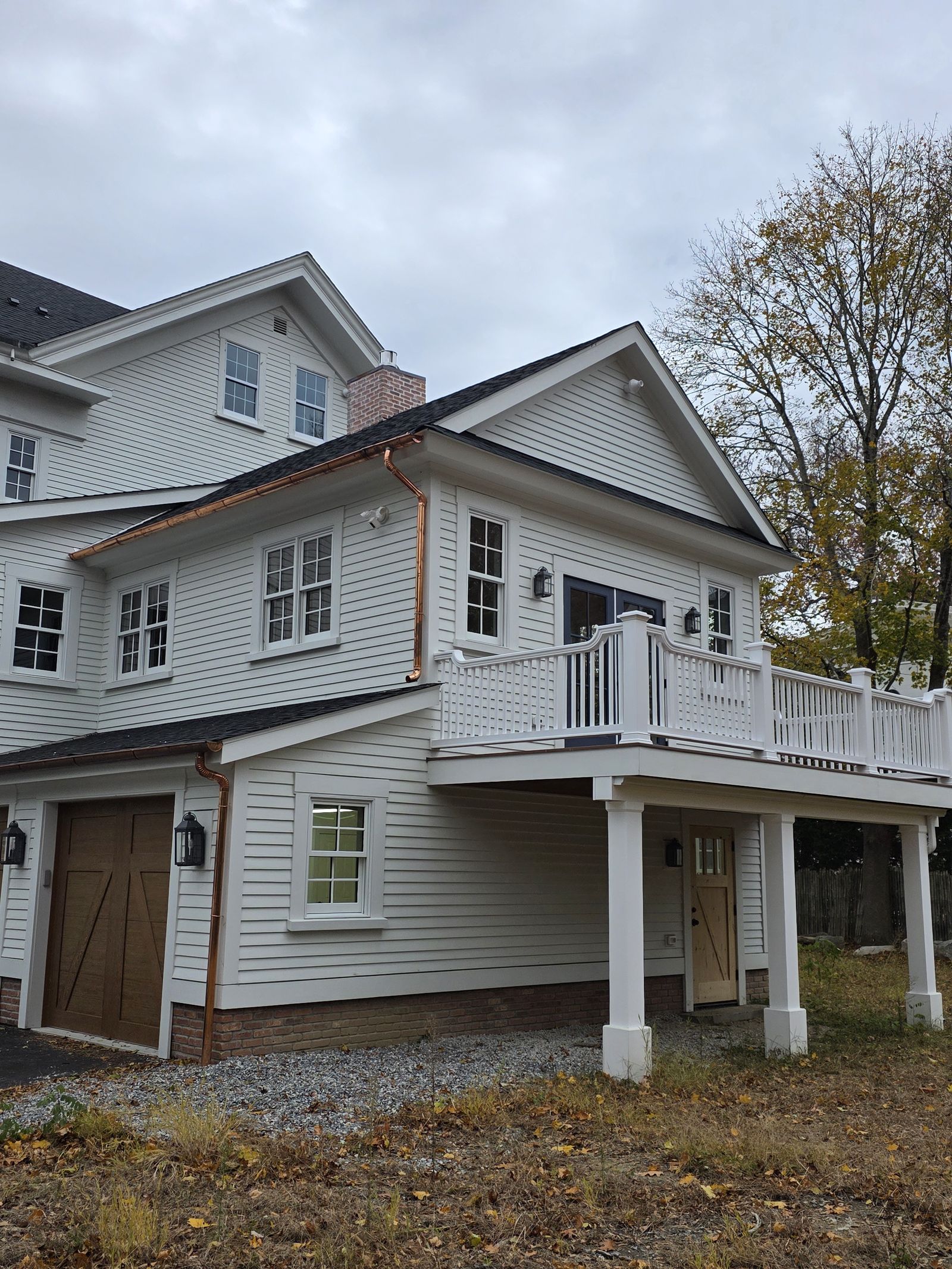 White clapboard home with copper gutters and second-floor deck