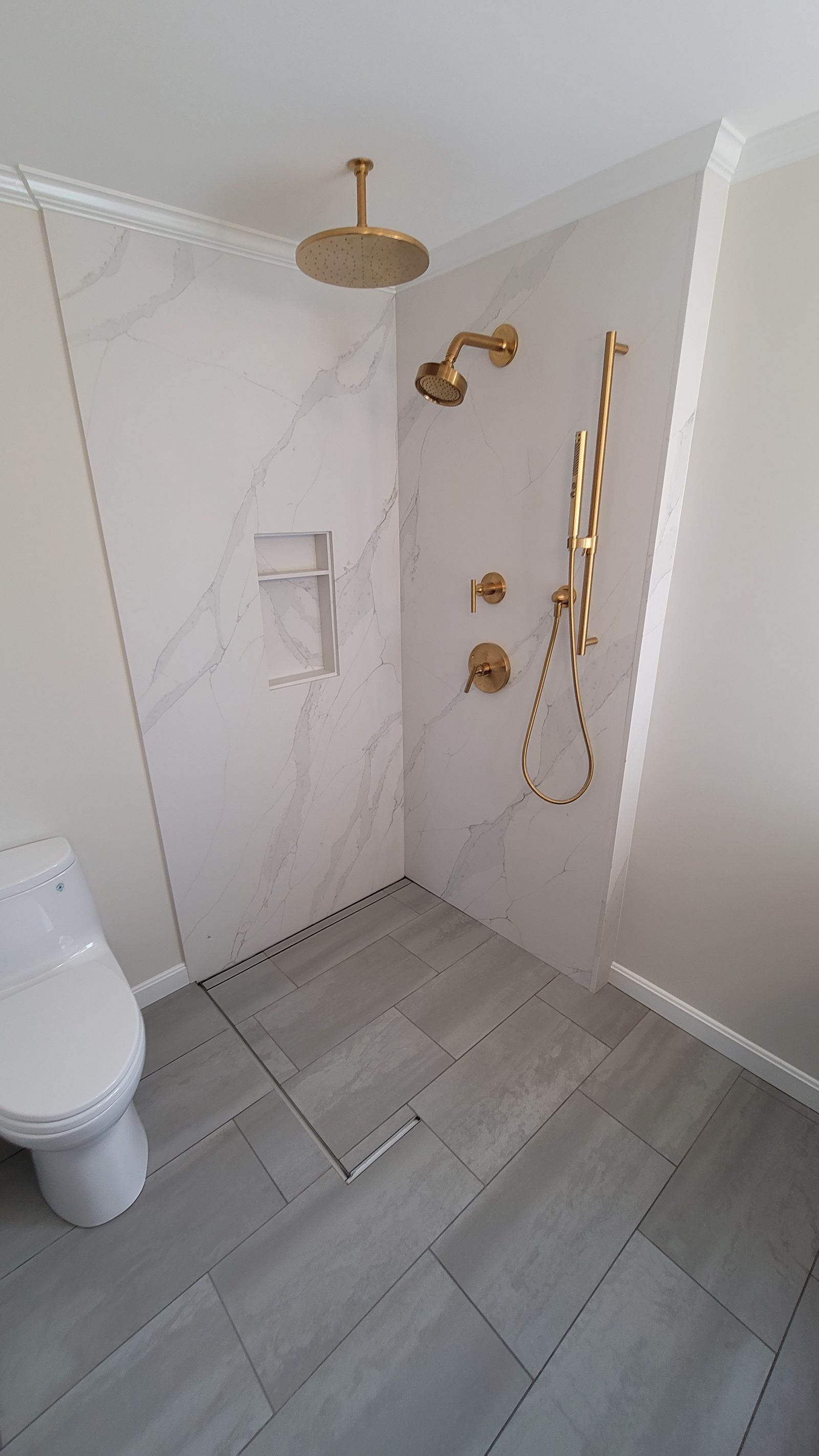 Curbless shower with quartz slab walls and brass fixtures