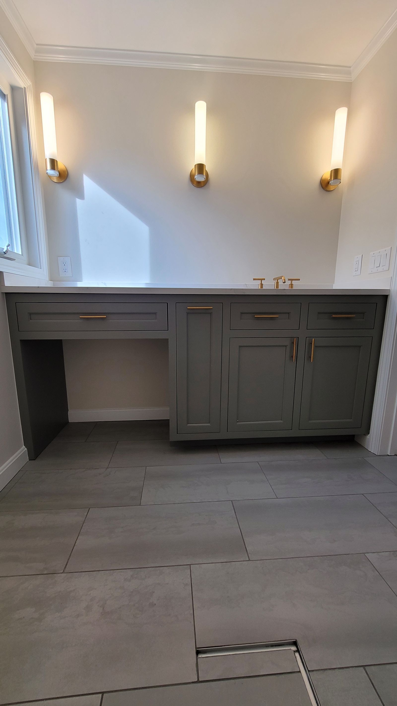 Gray inset vanity with makeup knee space and brass sconces