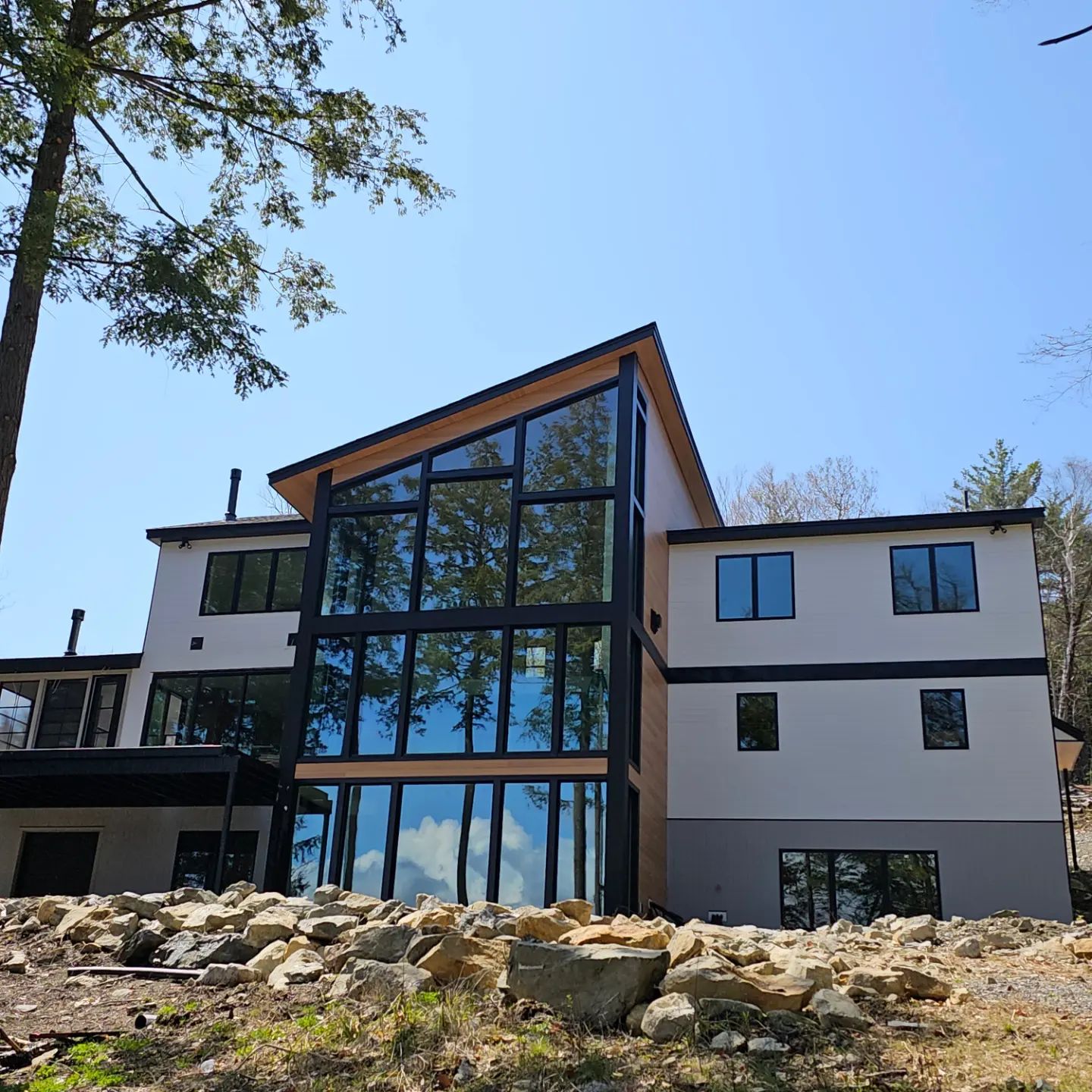 Modern custom home with a two-story glass wall among the trees