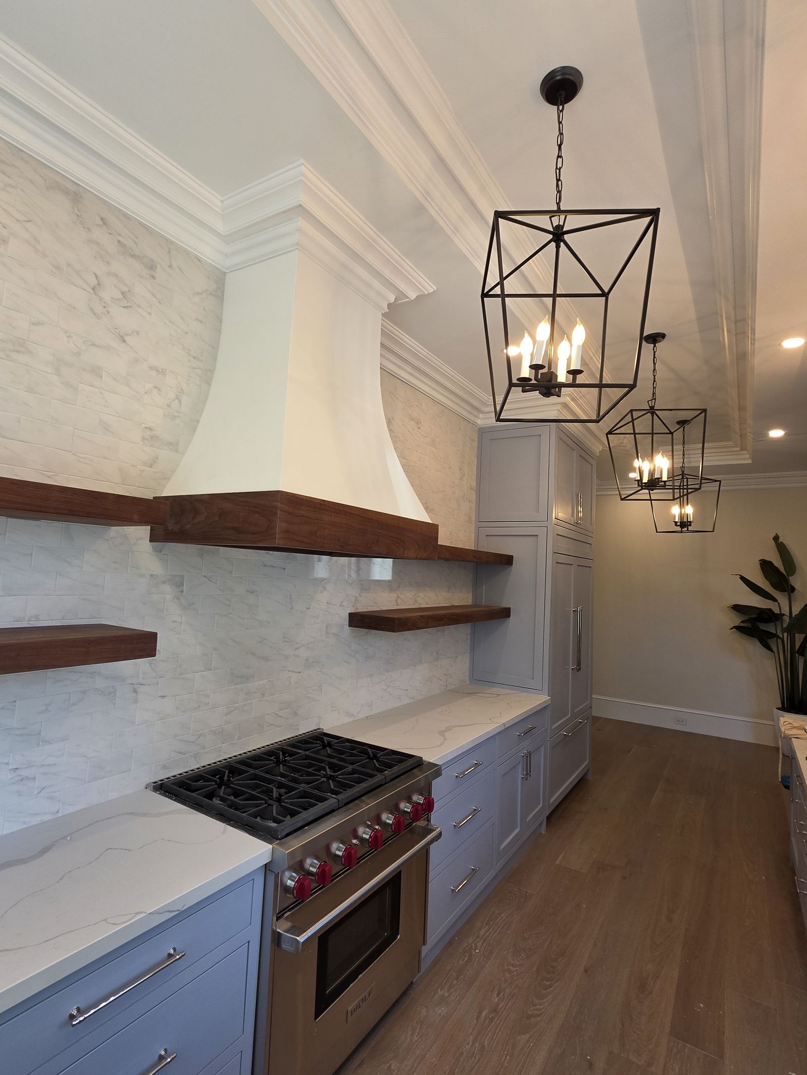 Plaster range hood with walnut band and lantern pendants